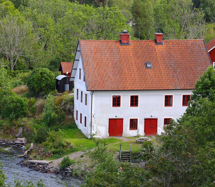 Kvinna i blå klänning står framför en vit byggnad med skylten Bränneriet