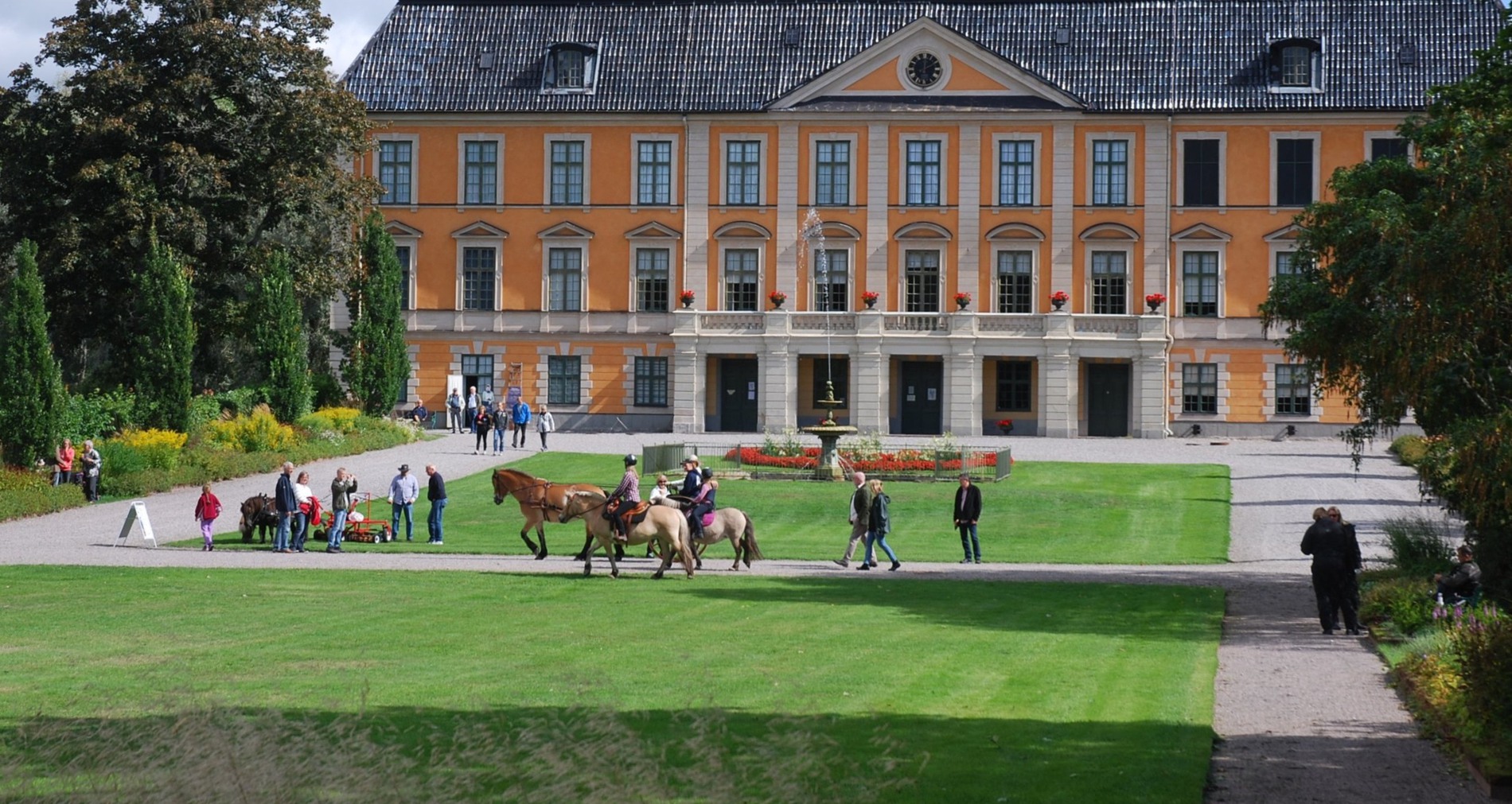 Nynäs slottspark i full grönska. I bakgrunden syns den gula slottsbyggnaden.