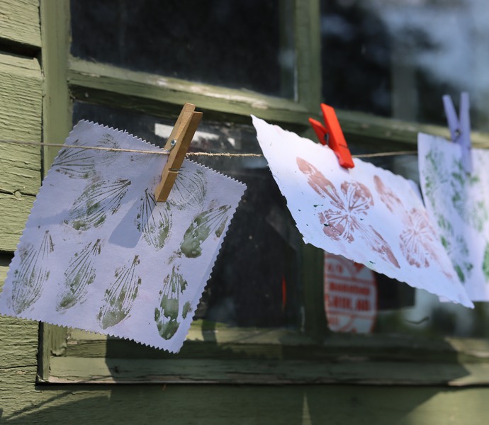 Papper med målade blommor hänger på tork och blåser i vinden.