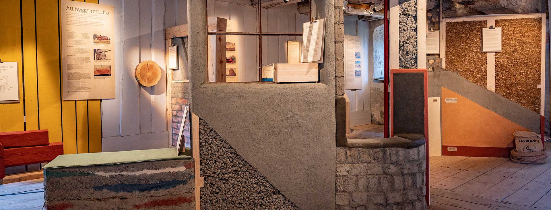 En interiörbild av utställningen Hållbara hus med lerväggar och linoljefärgade väggar.